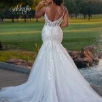 A bride in a long white wedding gown, turned back and striking a pose in an outdoor area, surrounded by trees and plants